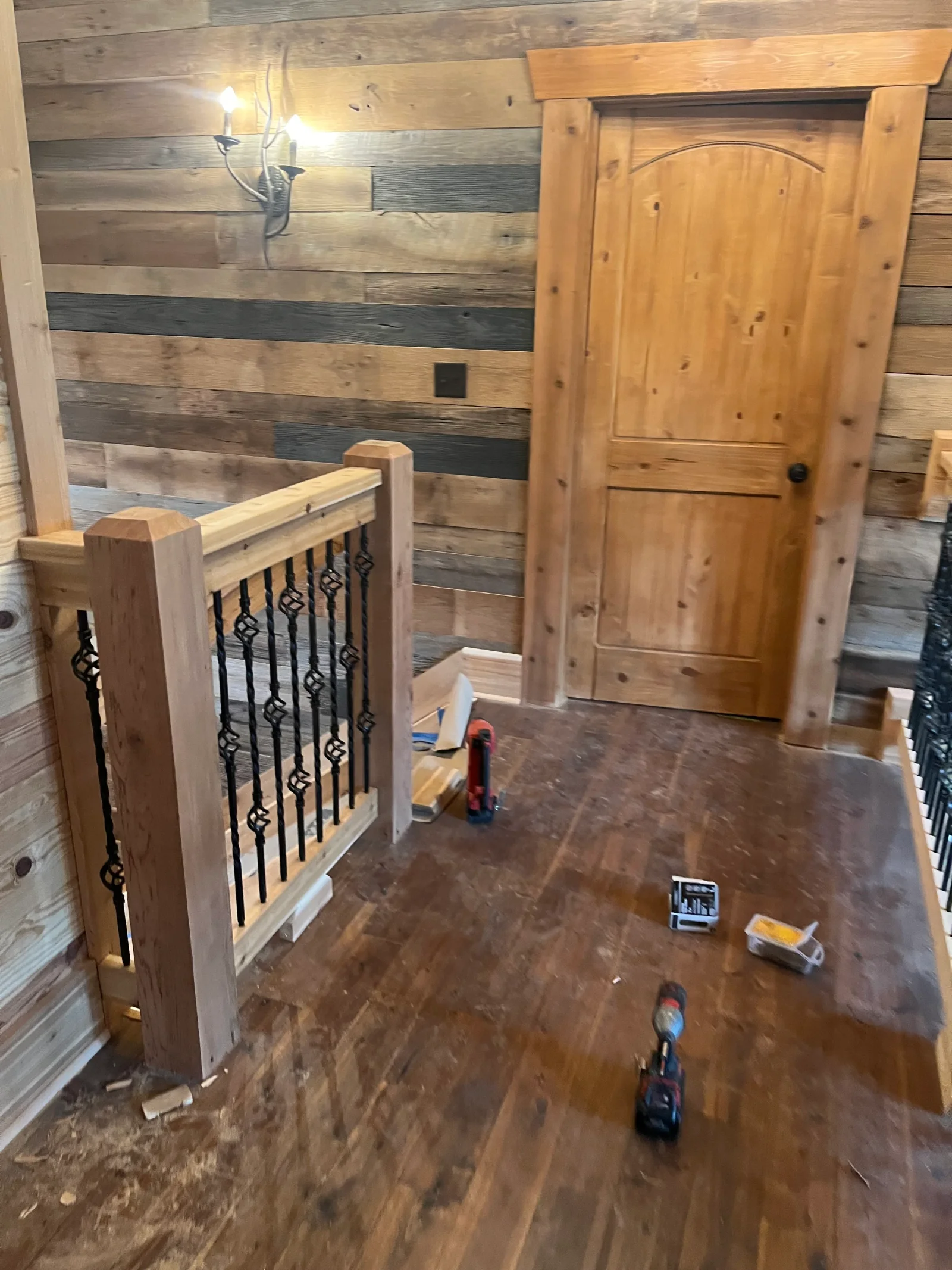 Mixed wood shiplap walls, wooden staircase with metal balusters, and custom wood cabinetry in rustic interior
