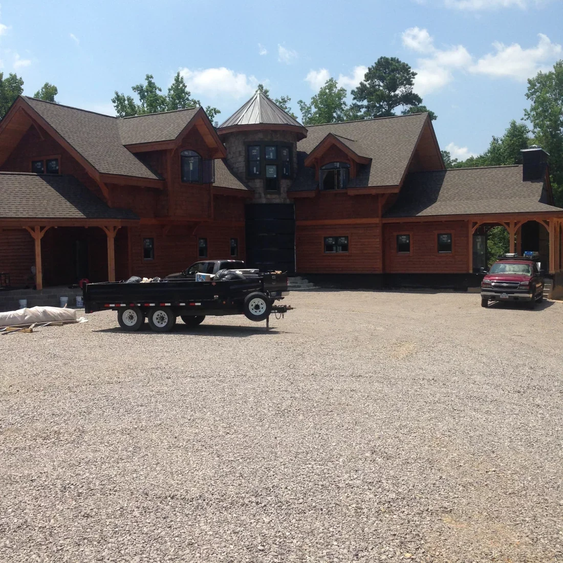 Red cedar siding and stone custom home with peaked roofs, turret tower, and multi-car garage