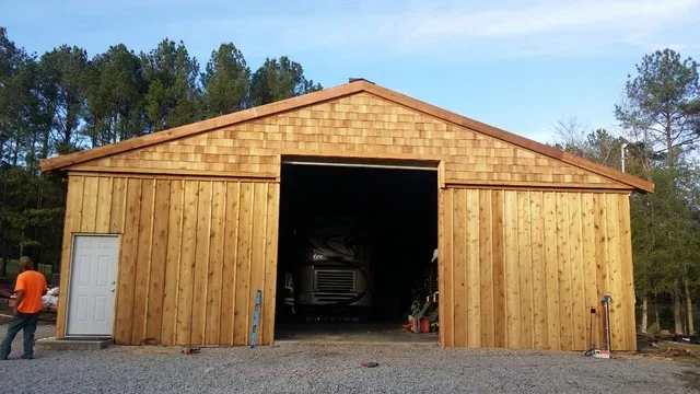 New wood-sided garage with cedar shingle roof and overhead door