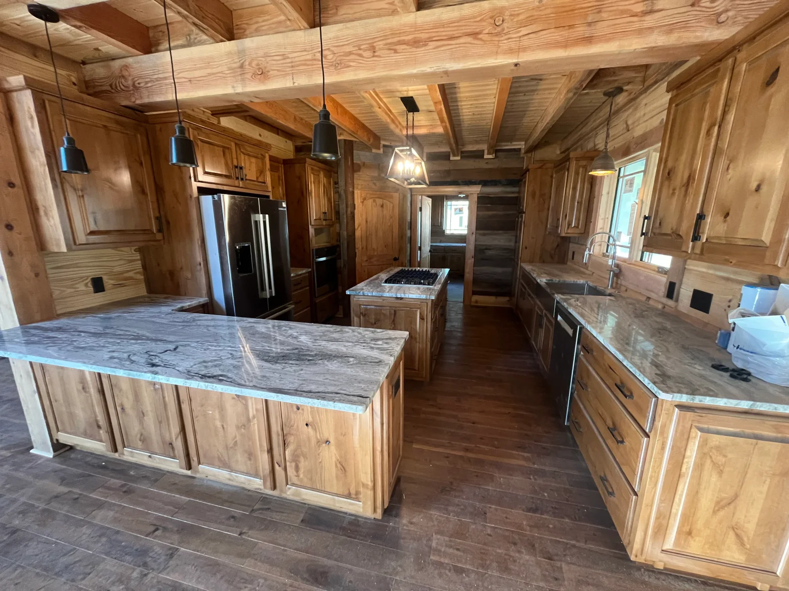 Spacious kitchen with knotty alder cabinets, marble countertops, exposed wood beams, and stainless steel appliances